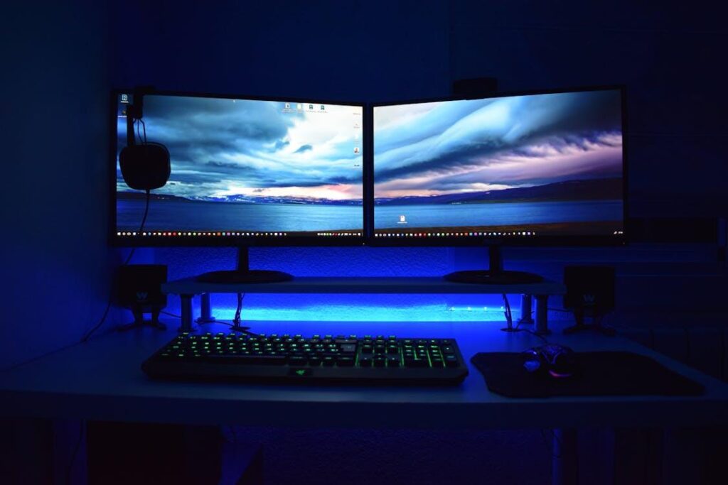 Free Dual monitors with blue lighting on a gaming desk setup. Stock Photo